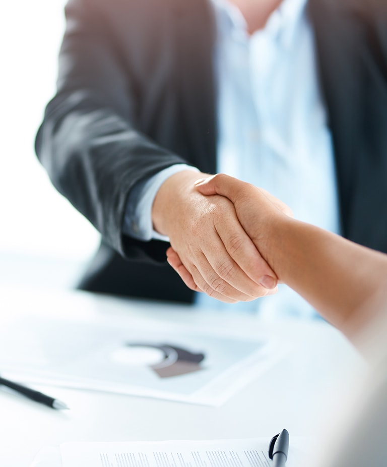 Two businesswomen shaking hands during a meeting in a modern office.